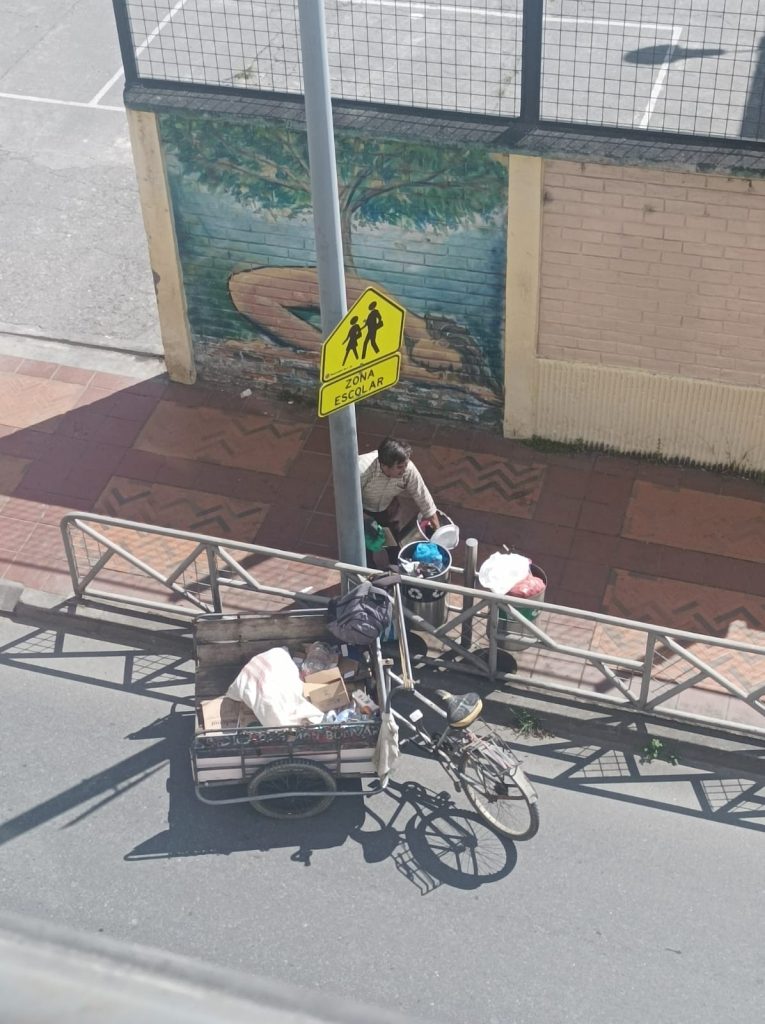 En la calle Olmedo y Mercadillo, un reciclador busca en las papeleras algún desecho no orgánico que le pueda servir.