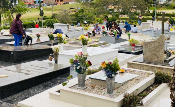 Familias visitan las tumbas de sus seres queridos, colocando flores y velas.
