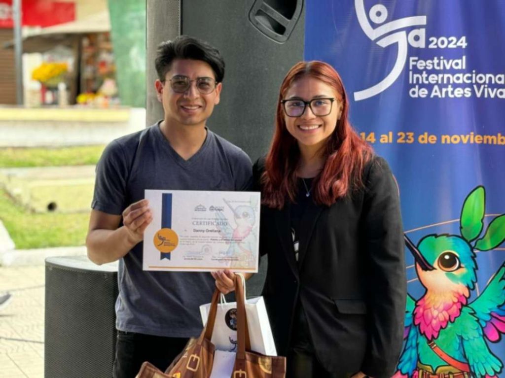 Danny Orellana, uno de los autores de la obra, recibe de la coordinadora municipal del Fiavl, Josselyn Llacxaguanga, una certificación.