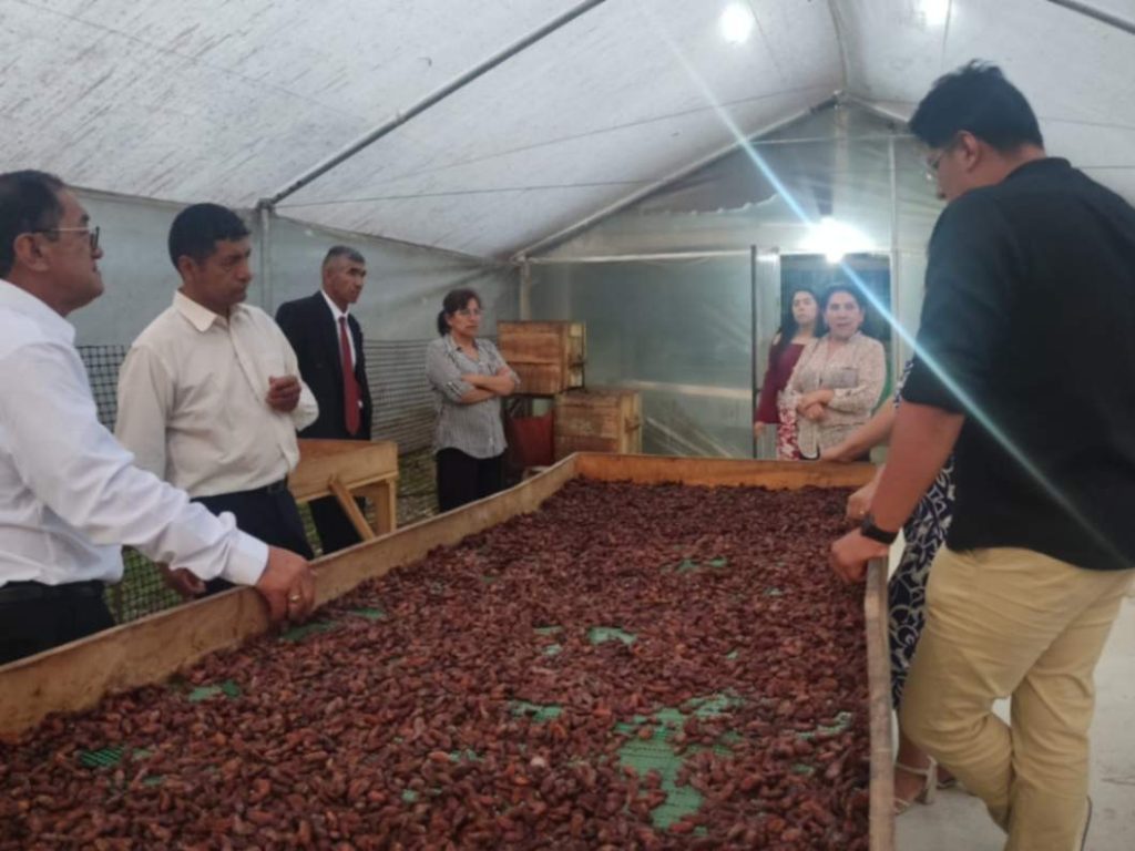 Franz Eduardo Guamán, responsable del emprendimiento (derecha), explica a los turistas el proceso del cacao, previo a la elaboración del chocolate.