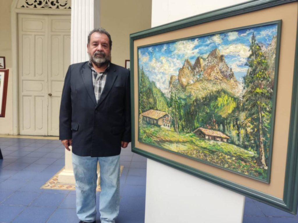 El artista lojano, junto a su primera obra, elaborada en 1979, que la solicitó en condición de préstamo para el evento del Paraninfo Universitario.