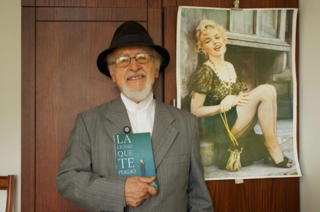 El autor muestra su libro La ciudad que te perdió, atrás, en un afiche, sobresale la actriz y modelo Marilyn Monroe, a quien admira. (Fotografía: Scarley Rodríguez Paucar)